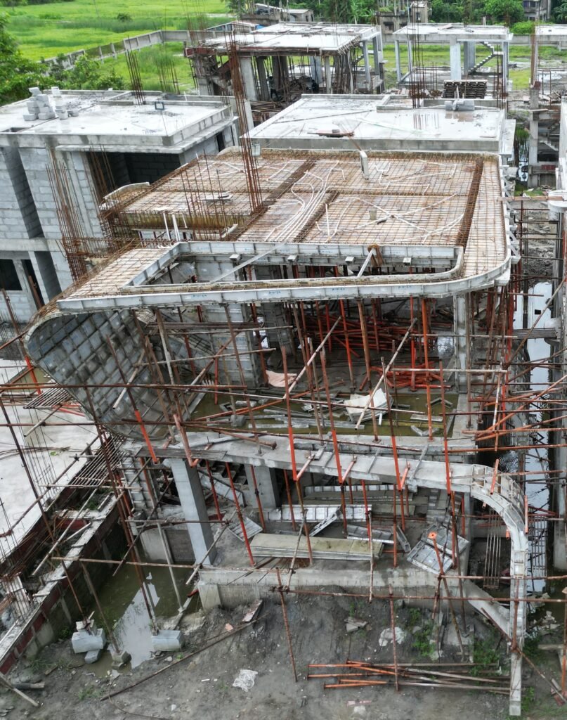 A building with curved floor edges under construction, supported by formwork and props
